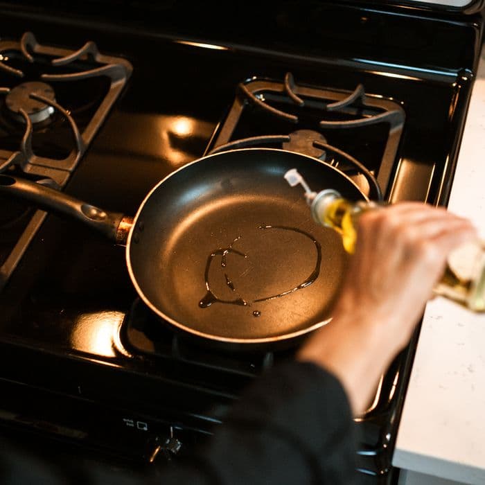 Olive oil poured into a hot frying pan on a gas stove