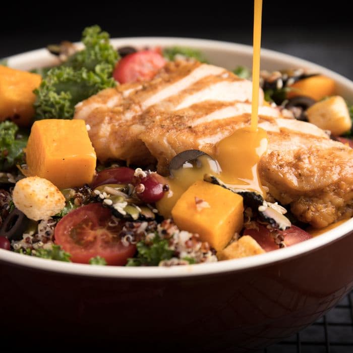 Dressing poured over a chicken and grain salad